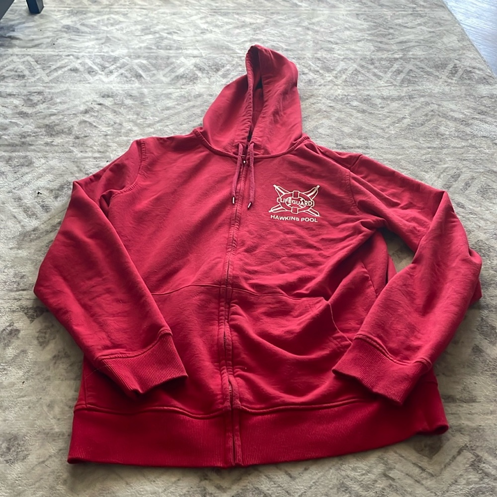 Small red zip up jacket with lifeguard of Hawkins pool logo